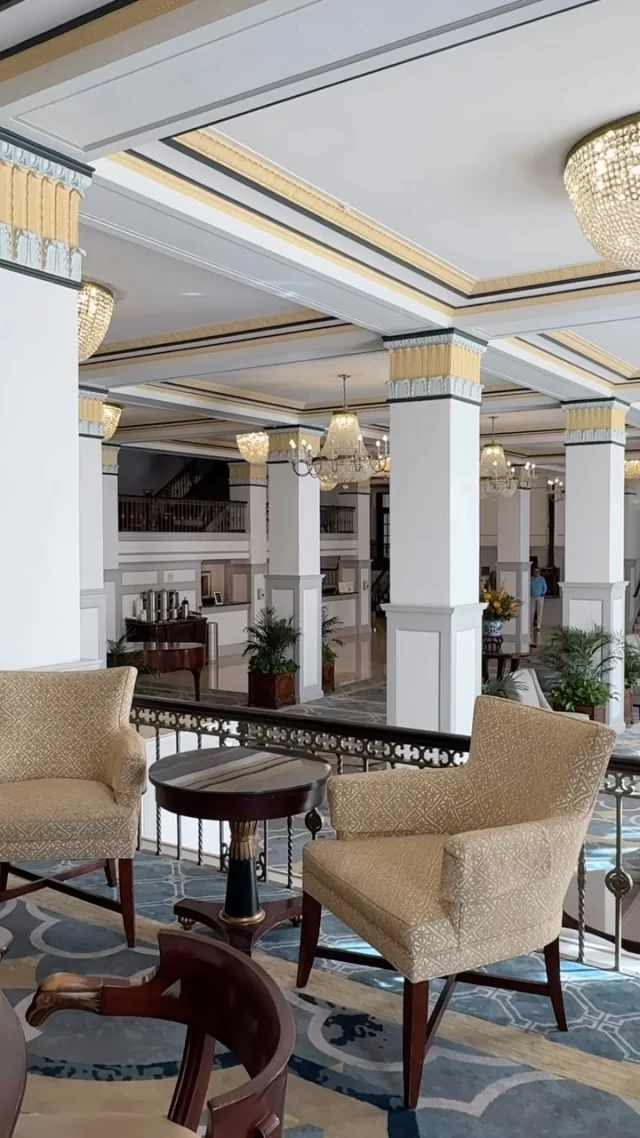 A luxurious lobby with a high ceiling, white columns, and elegant furniture.