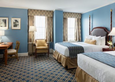 Two double beds are featured with blue and gold accents throughout the room.