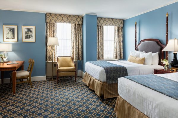 Two double beds are featured with blue and gold accents throughout the room.