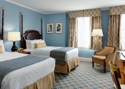 Two double beds are featured with blue and gold accents throughout the room.