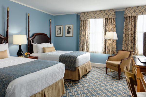 Two double beds are featured with blue and gold accents throughout the room.