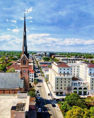 A view from our penthouse suite level shows king street and a tall church steeple. Its a bright and sunny day and cars line the street.