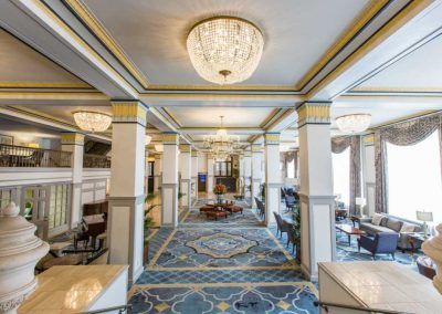 Our lobby features blue and gold accents throughout the floors and ceilings. Sitting room is to the right where large floor to ceiling windows let in an abundance of natural light. Large sparkling chandeliers hang throughout.