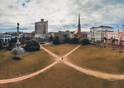 An aerial image of a bride and groom in the center of the Marion square park. The hotel and the city are along the skyline.