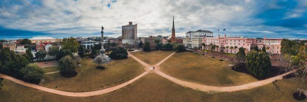 An aerial image of a bride and groom in the center of the Marion square park. The hotel and the city are along the skyline.