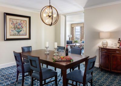 A dining room area is set with two large candles and a plate of meats and cheeses. A large exposed lightbulb fixture hangs above the table.