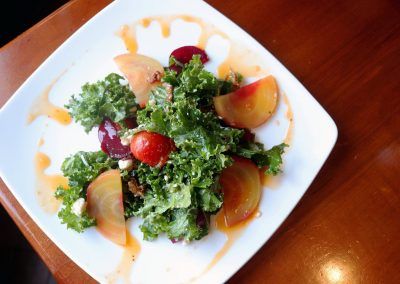A green salad with golden and red beets is drizzled with a orange vinaigrette.