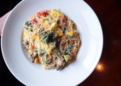 A bowl of pasta with colorful veggies.