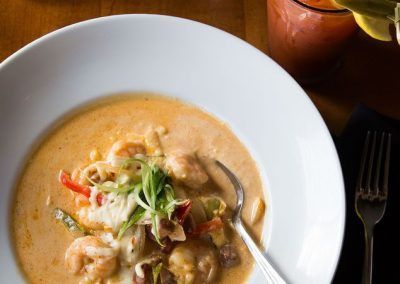 a plate of shrimp and grits with a bloody mary and a cup of coffee.