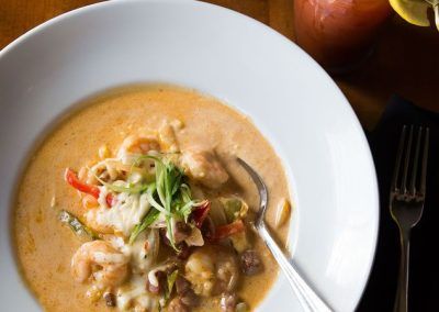 a plate of shrimp and grits with a bloody mary and a cup of coffee.