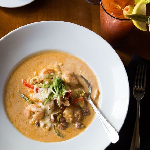 a plate of shrimp and grits with a bloody mary and a cup of coffee.